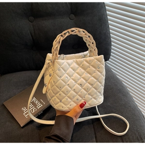 Detail of white quilted bucket bag featuring sparkling rhinestones and woven handle