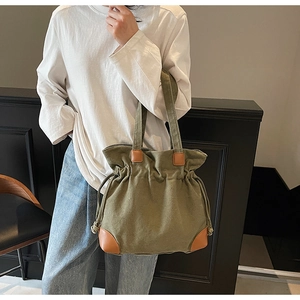 Close-up of drawstring canvas tote bag with brown leather corners and durable handles
