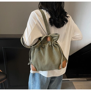 Deep green washed canvas backpack with brown leather trim shown on a model