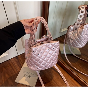 Macro detail of pearlescent pink bucket bag with quilted rhinestones and woven ring handle