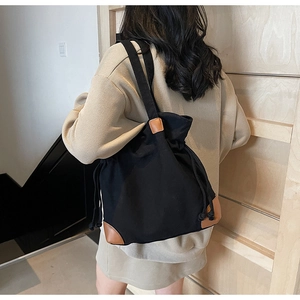 Detail of black drawstring nylon bag with vintage brown leather corner reinforcements