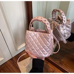 Detail of pink quilted bucket bag with rhinestones and woven top handle on mirror