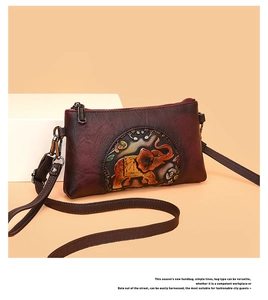 Close-up of vintage embossed elephant pattern on reddish-brown leather crossbody bag