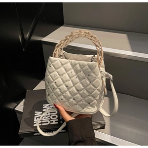 Detailed shot of white quilted handbag with crystal studs and braided knot handle