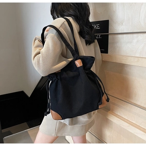 Détail du sac seau noir en nylon avec renforts en cuir marron et cordon serrage