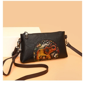 Detail of vintage black leather crossbody bag featuring an embossed elephant pattern medallion