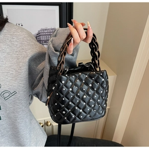 Detail of black quilted bucket bag with rhinestones and woven chain handle