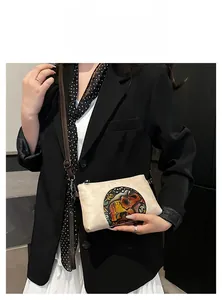 Detail of beige ethnic crossbody bag with colorful elephant embroidery and leather strap