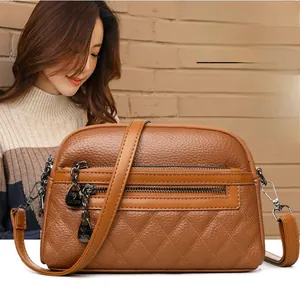 Detail of brown lychee leather crossbody bag with quilted stitching and double zipper pockets