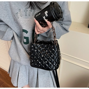 Detailed view of black quilted bucket bag with silver rhinestones and chain handle