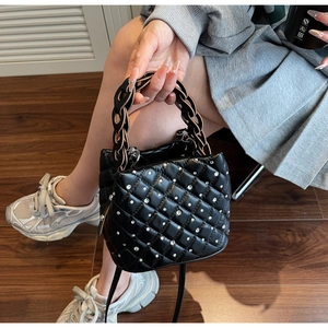 Detail of black quilted bucket bag with rhinestones and thick chain handle strap