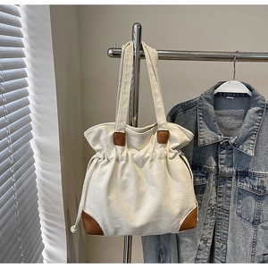 Détail du cabas en toile beige avec fermeture à cordon et coins renforcés en cuir