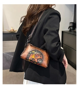 Detail of red-brown leather crossbody bag featuring a hand-painted elephant relief pattern