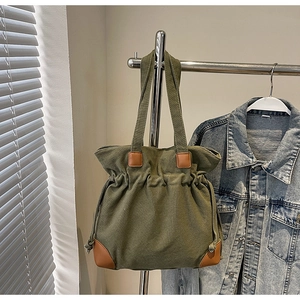 Gros plan du sac fourre-tout en toile vert foncé avec empiècements en cuir et cordon