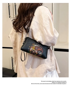 Detail of black leather crossbody bag featuring an embossed elephant pattern on the surface