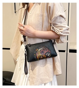 Detail of black crossbody bag with colorful round elephant embossing and adjustable strap