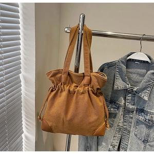 Détail du sac seau en nylon avec finitions cuir et cordon de serrage sur cintre