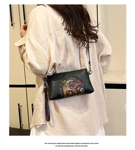 Close-up of vintage black leather bag featuring colorful embossed elephant pattern details