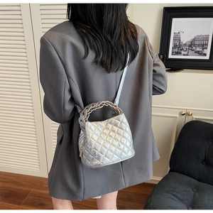 Close-up of silver quilted crossbody bag with diamond accents and braided handle