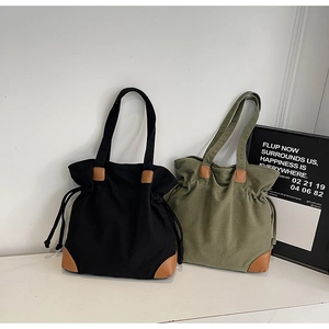 Détails de cabas en toile noire et vert olive avec des renforts en cuir marron élégants