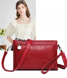 Detail of red crossbody clutch with mixed crocodile and snakeskin patterns and vintage metal zipper