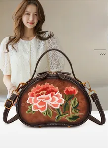 Close-up of vintage brown leather bag featuring intricate red peony floral embroidery