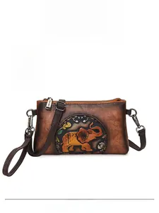 Detail of yellow brown embossed leather handbag with golden elephant and floral patterns