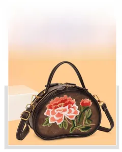 Close-up of retro floral embroidery on brown crossbody bag with gold metal zippers