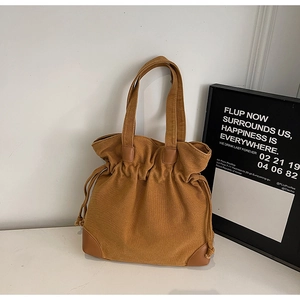 Detail of dark camel nylon bucket bag featuring faux leather corners and drawstring closure
