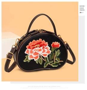 Detail of floral embroidery and contrast stitching on a black kidney shaped handbag