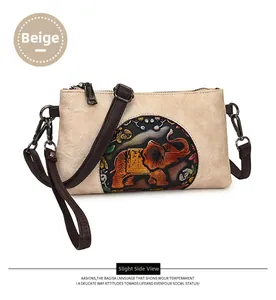Detail view of beige envelope bag with colorful embossed elephant and vintage finish
