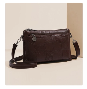 Detail of dark brown faux crocodile leather clutch with multiple zipper pockets