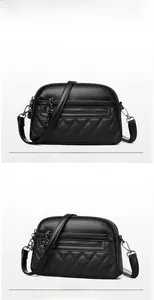Detail of black pebbled leather crossbody bag with diagonal quilting and zipper layers
