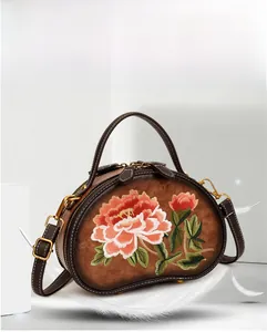 Detail of vintage brown leather bag featuring floral embroidery and gold hardware