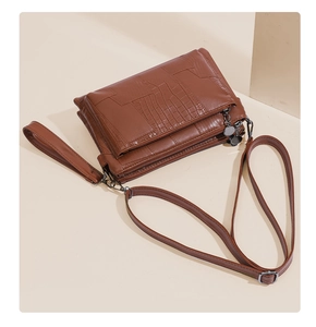 Detail view of brown crocodile texture leather bag with adjustable strap and wristlet