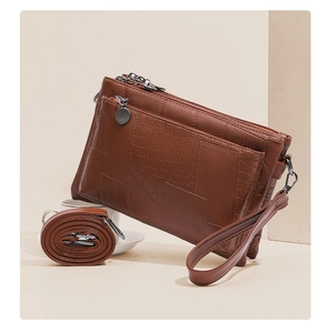 Detail of brown croc-embossed patchwork handbag with silver zippers and long shoulder strap