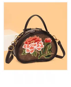Close-up of vintage brown leather handbag featuring detailed red peony flower embroidery