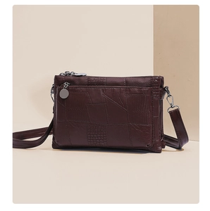 Detail of dark brown crocodile and snake embossed textures on faux leather crossbody bag