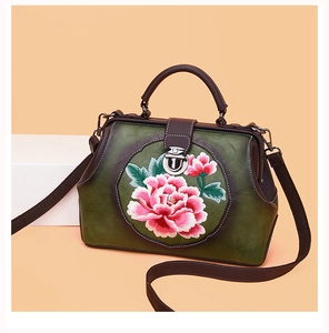 Macro detail of Chinese peony embroidery on dark green vintage leather handbag