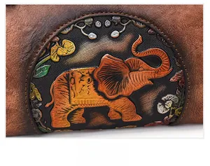 Detailed close-up of retro brown leather bag featuring an embossed elephant and floral pattern