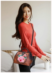Detail of vintage brown leather bag featuring exquisite peony flower embroidery and metal buckle