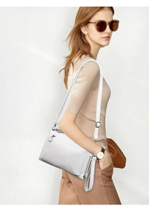 Detail of white crocodile texture PU crossbody bag with silver hardware and round charm