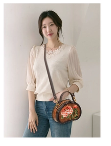 Brown round crossbody bag with peony embroidery shown on a model with denim and lace