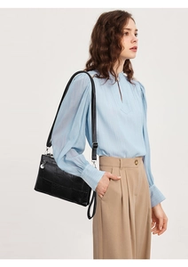 Close-up of black PU leather crossbody bag with textured embossing and silver hardware