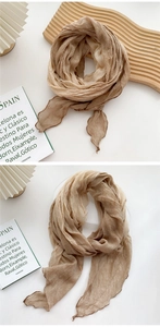 Close-up of lightweight khaki linen scarf featuring wavy curled edges and soft textures