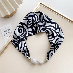 Detail of silk scarf with black rose print, silver magnetic buckle and crystal pendants
