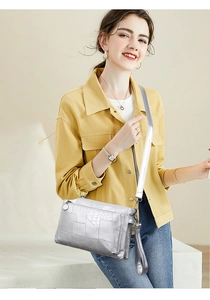 Detail of silver crocodile-embossed PU leather bag with triple zip compartments and strap