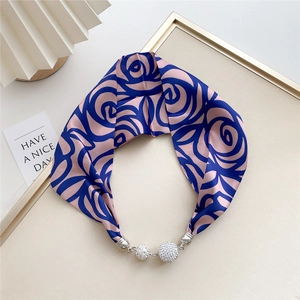 Detail of silk scarf necklace featuring blue rose print and rhinestone sphere magnetic buckle