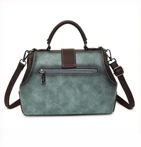 Detail of teal and brown leather handbag showing white stitching and rear zipper pocket