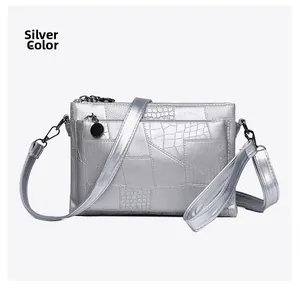 Detail view of silver textured PU leather envelope bag with crossbody strap and charms